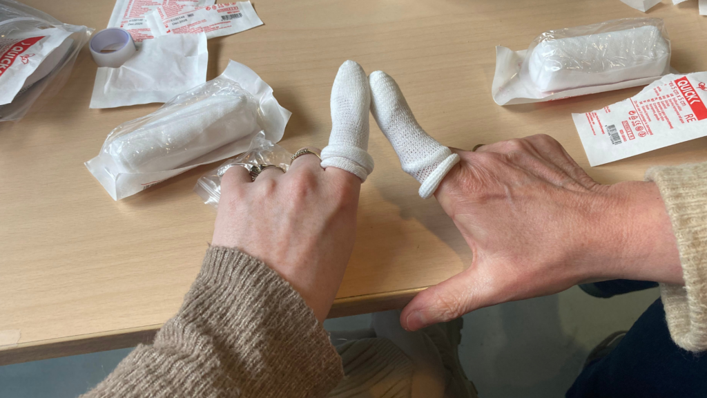 Twee deelnemers hebben succesvol een verband om de wijsvinger gelegd en steken de vingers bij elkaar.